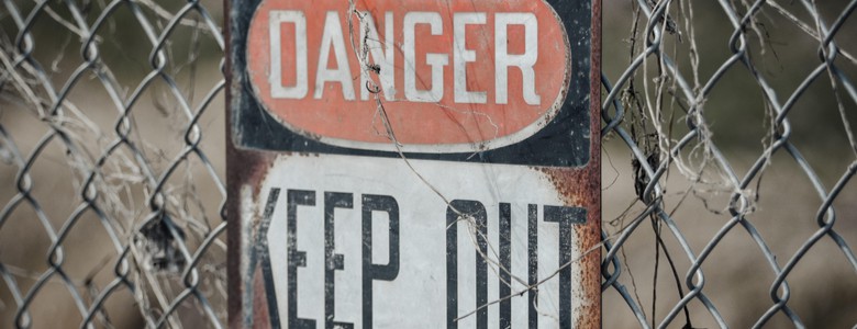 A rusty “Danger: Keep Out” sign on a chain-link fence