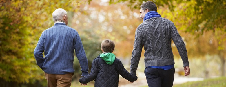 Three male generations of a family walking along a woodland path