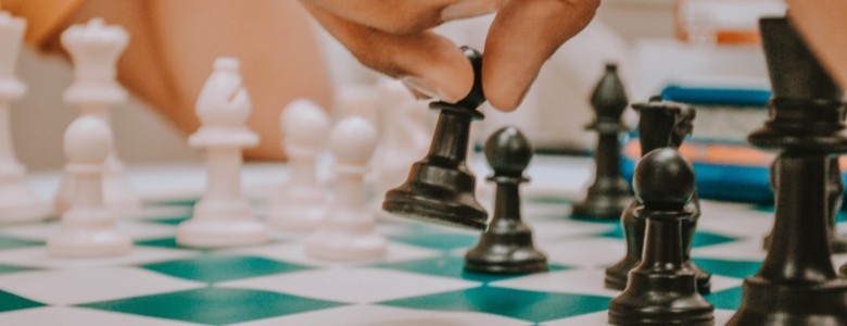 A close-up of a hand moving a pawn on a chessboard