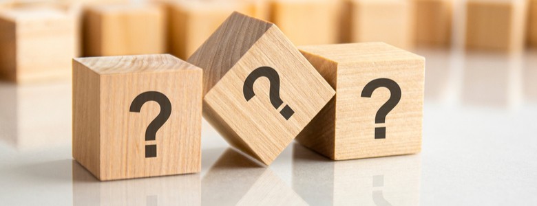 Three wooden blocks with question marks on them in a line