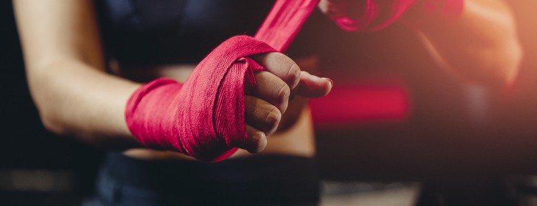 A woman wrapping bandages around her fists before a boxing match