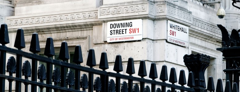 Road signs reading “Downing Street” and “Whitehall” attached to the corner of a building