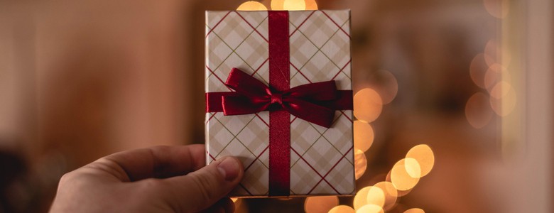 A small, gift card-sized Christmas present wrapped with a red bow