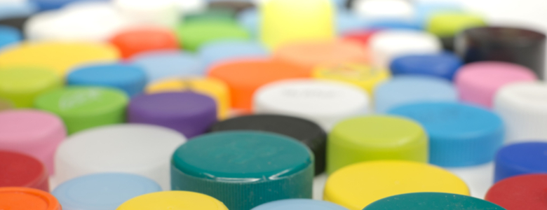 Different coloured bottle tops arranged against a solid background