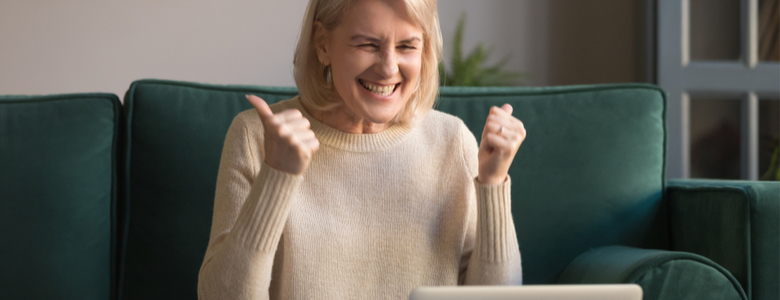A mature lady looking excitedly at a laptop